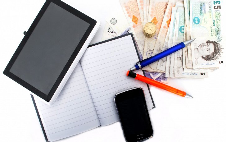 Ручка, блокнот, планшет и деньги на рабочем столе